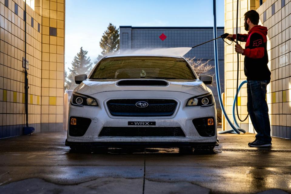 Man washing white car with hose