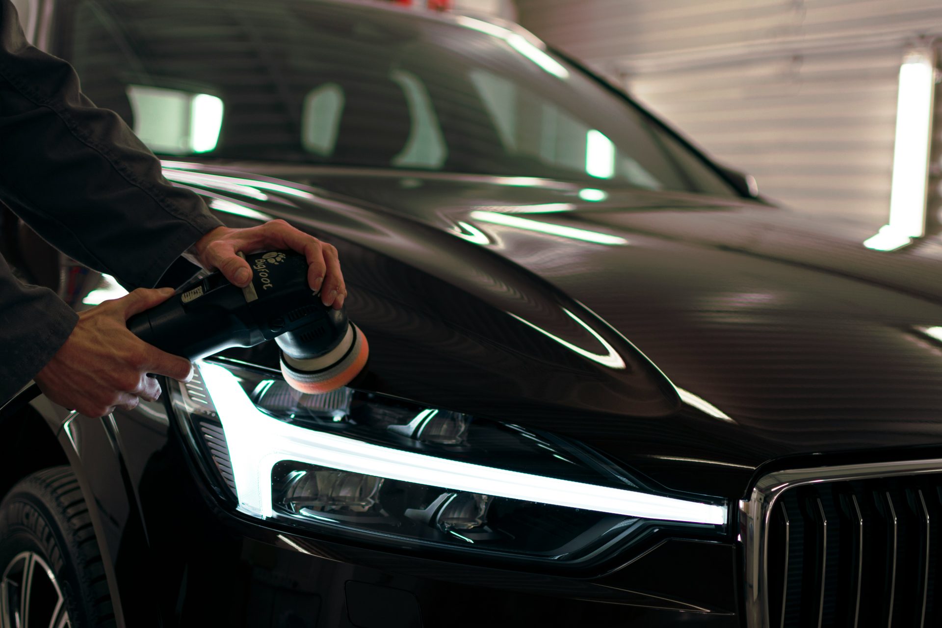 Car undergoing headlight polishing in workshop