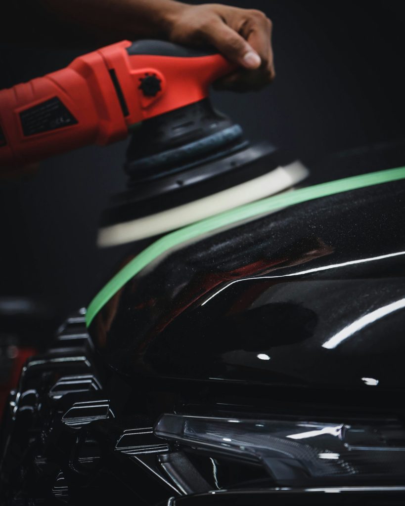 Polishing car's hood with red buffer