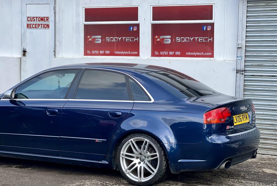 Blue car parked outside automotive repair shop.