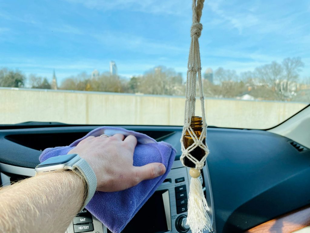 Hand wiping dashboard inside a car.